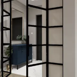 Nowoczesne wnętrze przedpokoju z granatową komodą, lustrem w złotej ramie, kwiatami i czarną ścianką działową ze szprosami.