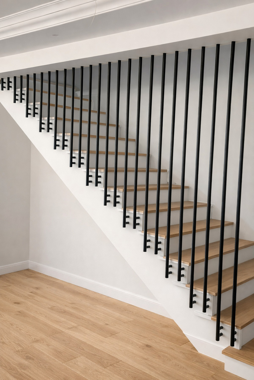 Minimalistyczne schody z drewnianymi stopniami i czarną, pionową balustradą. Jasne drewno podłogi i białe ściany tworzą nowoczesny kontrast.