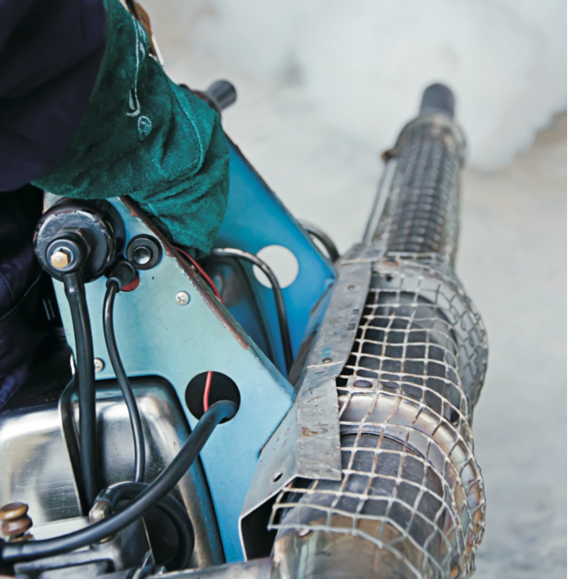 Urządzenie do zamgławiania z metalową siatką ochronną na dyszy, generujące gęstą parę, z widocznymi przewodami i elementami konstrukcyjnymi.