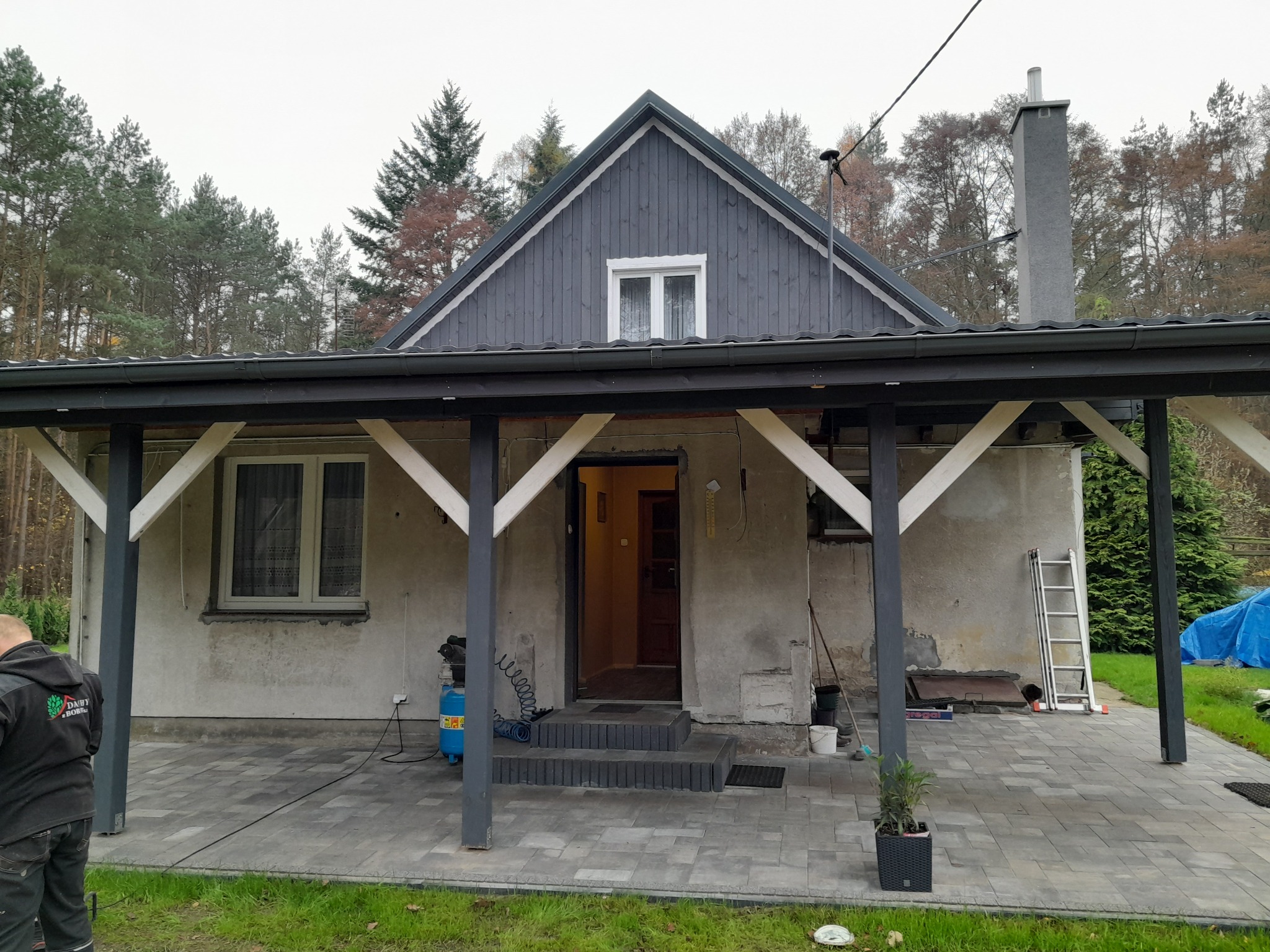 Dom jednorodzinny przed pracami elewacyjnymi, widoczne ślady po wcześniejszych naprawach, rusztowanie i narzędzia przygotowane do rozpoczęcia robót.