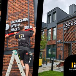 ReklaMaster MONIKA SZCZĘSNA - Montaż szyldów z nazwami firm na ceglanej elewacji budynku. Widoczne litery przestrzenne i pracownik na drabinie podczas instalacji. Szyldy w kolorach bieli i czerni.
