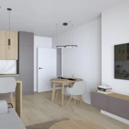 Wnętrze małego mieszkania z aneksem kuchennym, okrągłym stołem jadalnym i szarą sofą, oświetlone wiszącymi lampami z czarnymi elementami, minimalistyczny design.