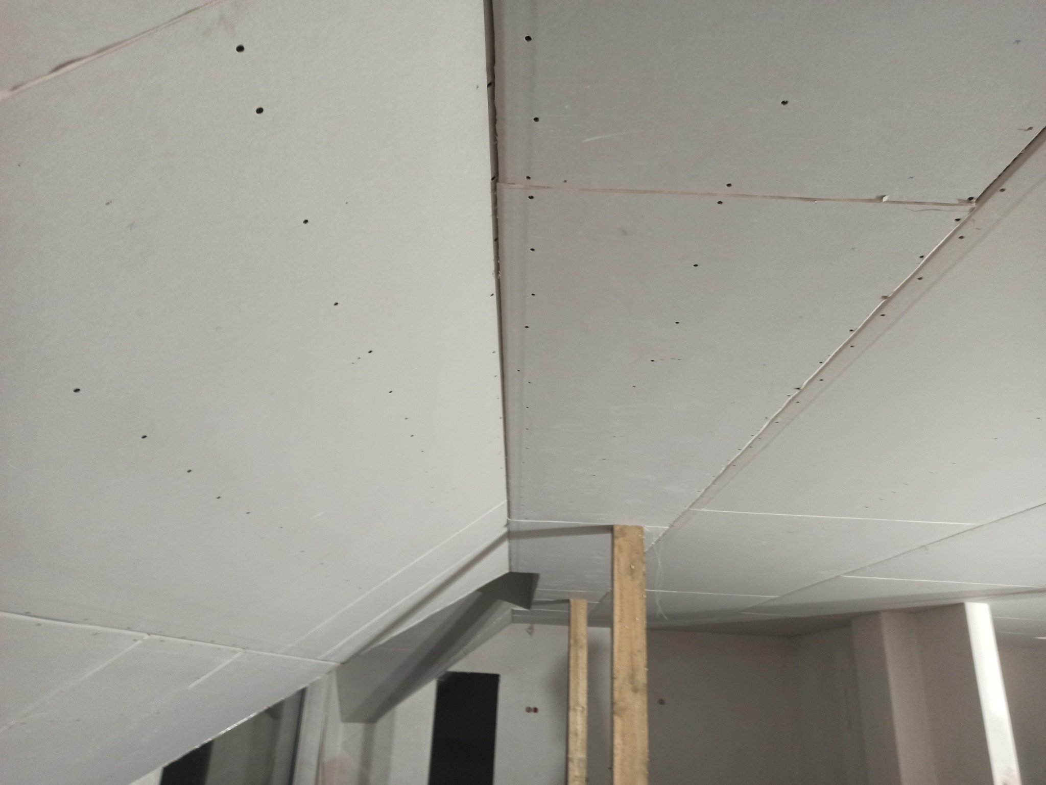 Montaż sufitu podwieszanego z płyt karton gips, widoczne łączenia i drewniane podpory