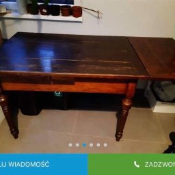 Czarny usługi budowlane - Stary, drewniany stół z wysuwanym blatem i toczonymi nogami, widoczne ślady użytkowania i odnowiona powierzchnia, na tle ściany z parapetem.