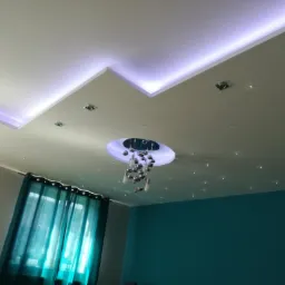 Sufit z podwieszanym elementem z oświetleniem LED, dekoracyjnymi punktami świetlnymi imitującymi gwiazdy oraz nowoczesnym żyrandolem z chromowanymi kulami, widok z dołu.