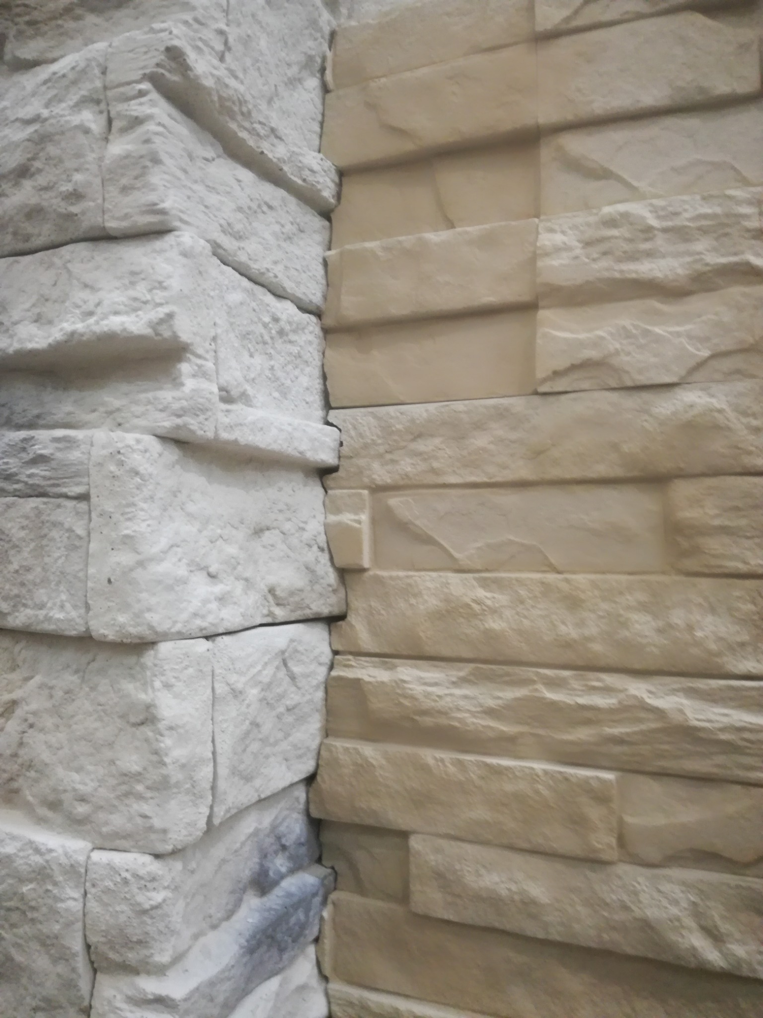 Połączenie dwóch rodzajów okładziny ściennej imitującej kamień: szarej na rogu i beżowej na ścianie, z widoczną fakturą i nieregularnymi kształtami.