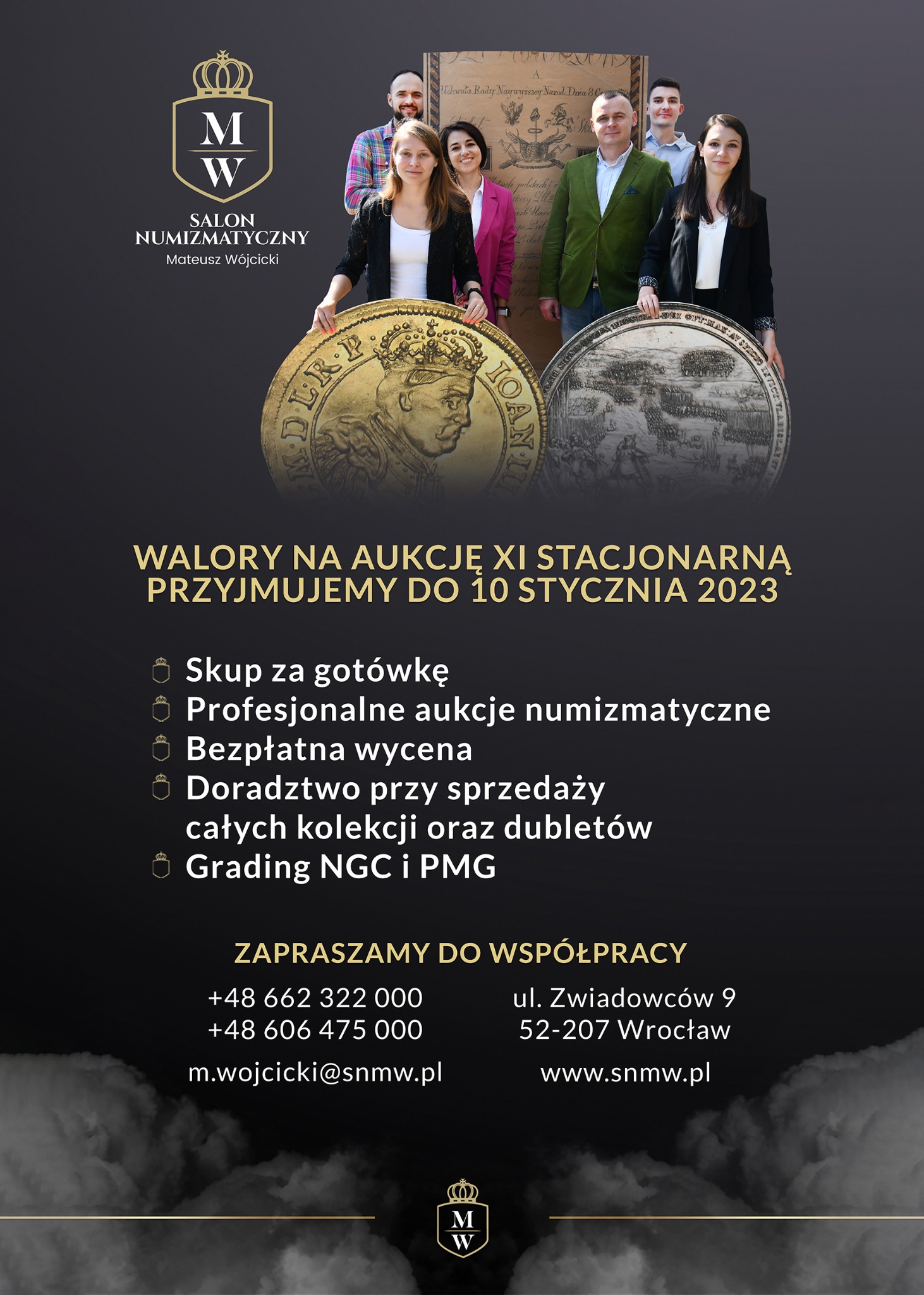 Zespół salonu numizmatycznego prezentuje złote i srebrne monety o dużej średnicy na tle plakatu z informacjami o aukcji.