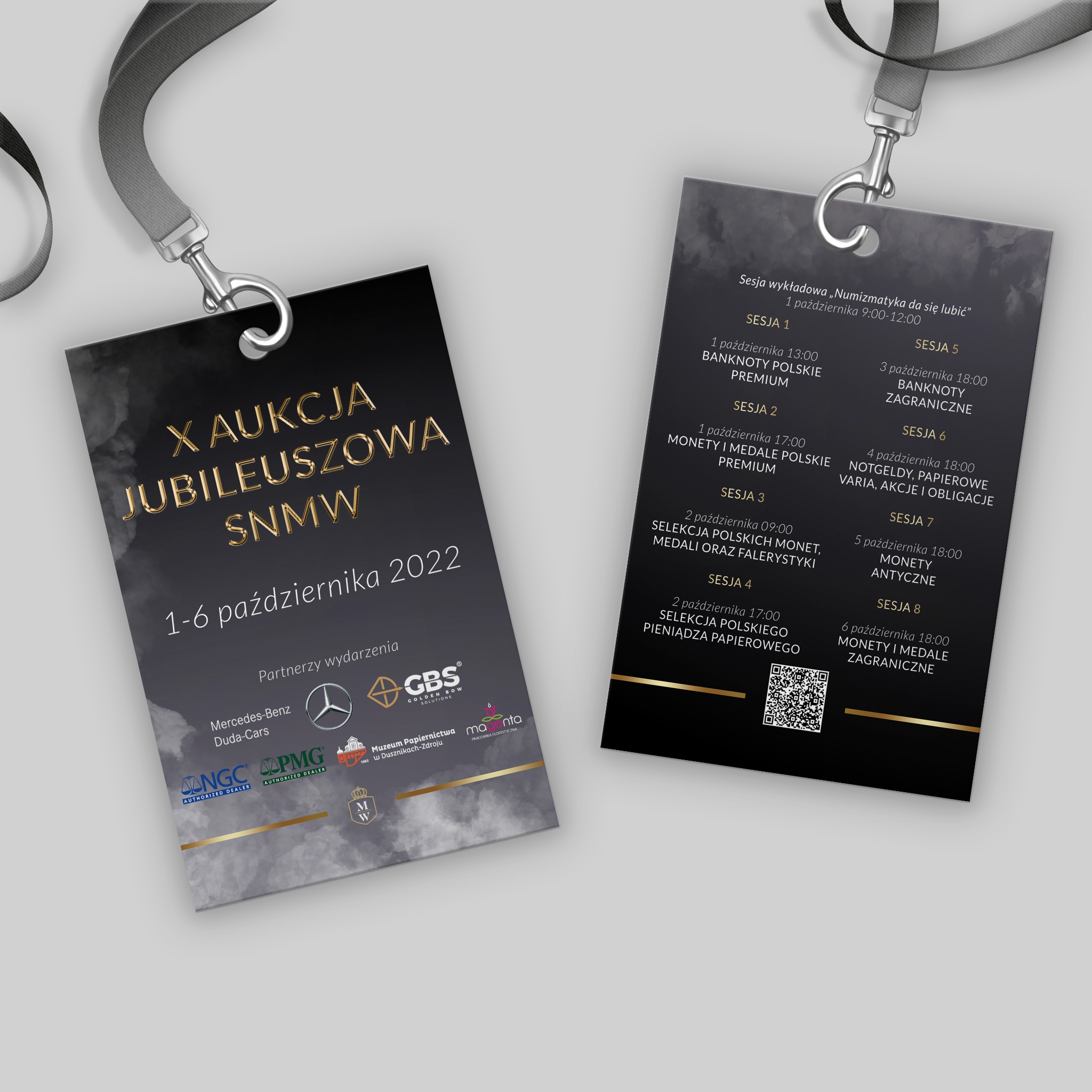 Dwa identyfikatory na smyczach, zapowiadające jubileuszową aukcję numizmatyczną, z listą partnerów wydarzenia, w tym Mercedes-Benz Duda-Cars i Muzeum Papiernictwa.