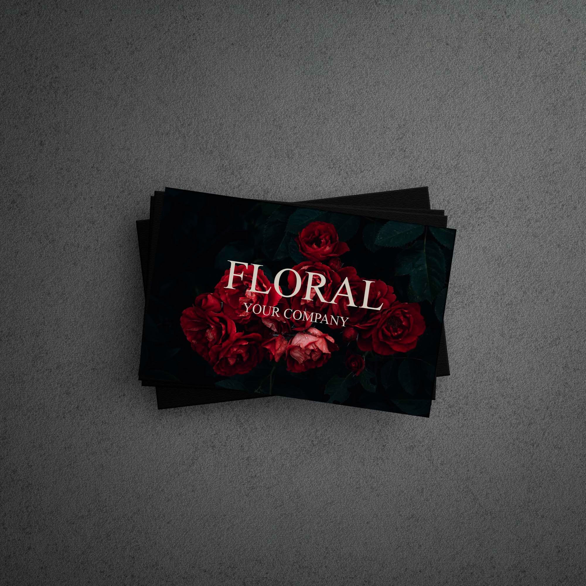 Stos czarnych wizytówek z ciemnym motywem kwiatowym i napisem 'FLORAL YOUR COMPANY' na szarym teksturowanym tle.