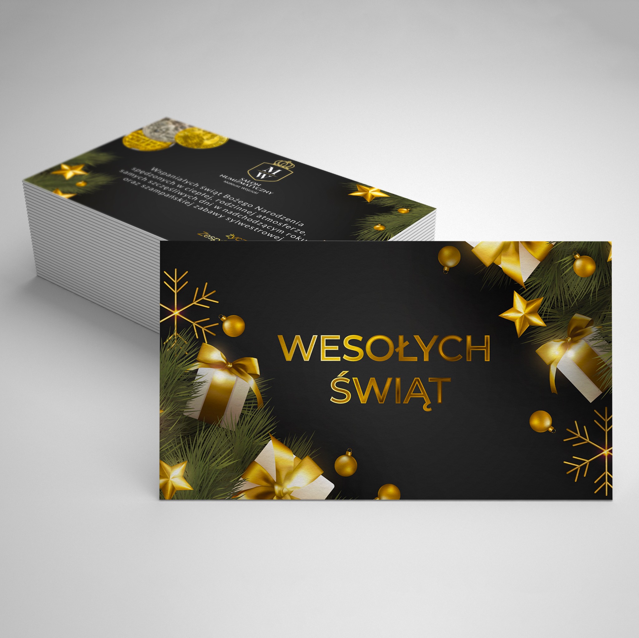 Stos wizytówek z bożonarodzeniowym motywem: złote napisy, prezenty i dekoracje na czarnym tle. Wizytówka firmy Salon Numizmatyczny.