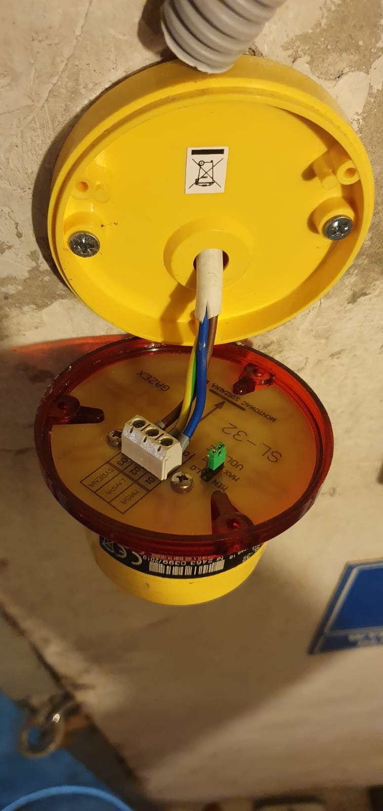 Żółto-czerwona czujka pożarowa GAZEX SL-32 zamontowana na suficie, widoczne podłączenie kabli elektrycznych do złączki.