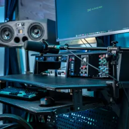 Profesjonalne stanowisko do nagrywania z mikrofonem Shure, mikserem Dynawid, monitorem Flightcore i głośnikami studyjnymi ADAM Audio w tle.