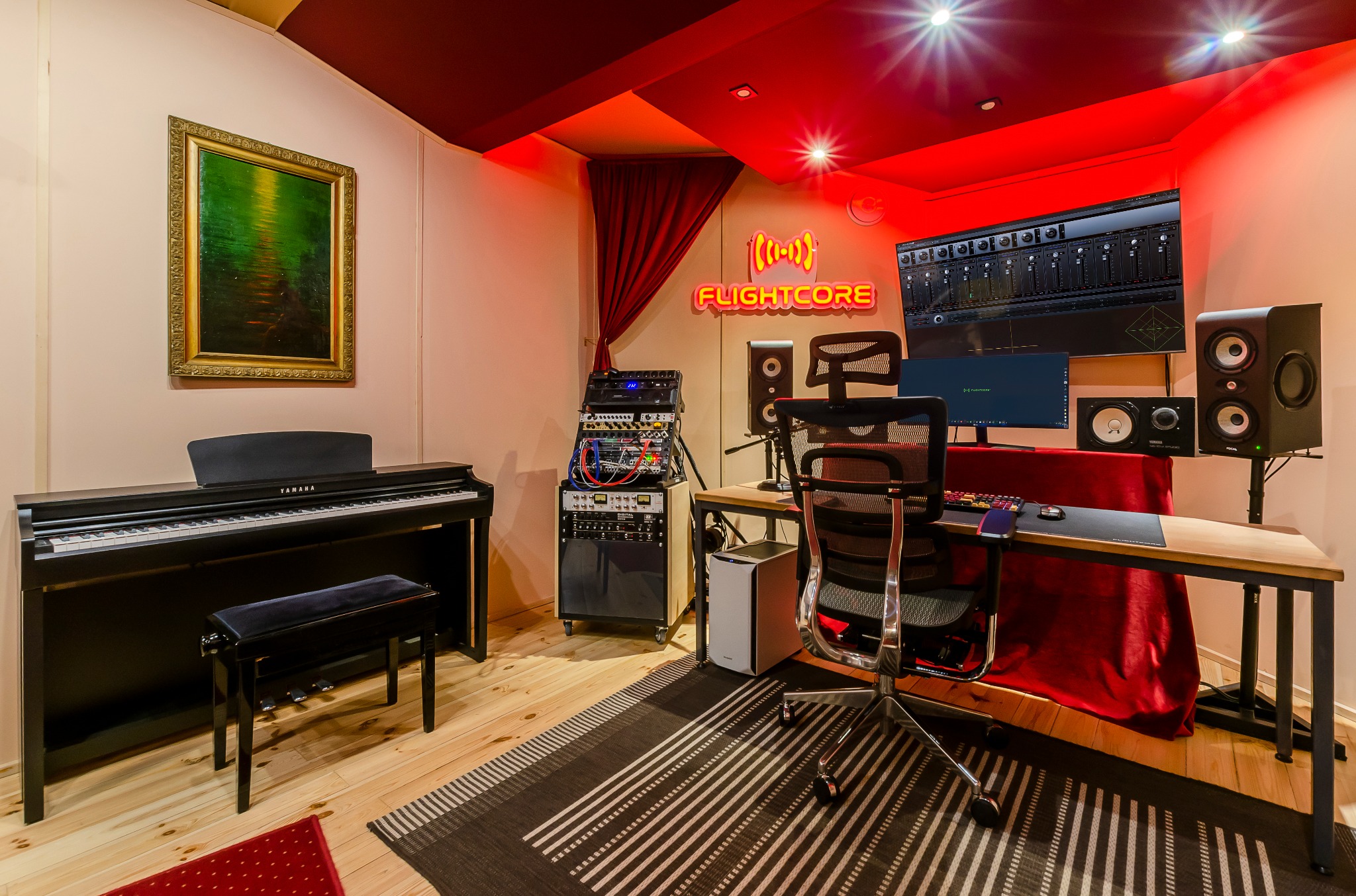 Profesjonalne studio nagrań z pianinem Yamaha, sprzętem rackowym, monitorami studyjnymi Focal, oświetleniem LED i neonem z nazwą studia Flightcore.