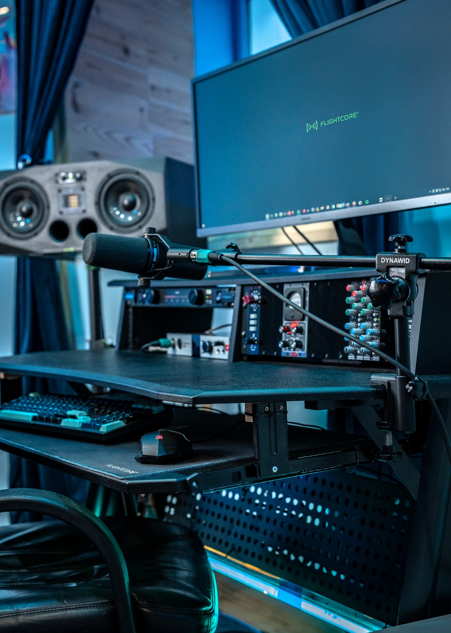 Profesjonalne stanowisko do nagrywania z mikrofonem Shure, mikserem Dynawid, monitorem Flightcore i głośnikami studyjnymi ADAM Audio w tle.