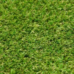 Bliski kadr na zieloną, syntetyczną trawę z rolki, ukazujący strukturę włókien i ich odcienie.