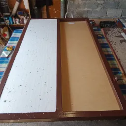 Rama metalowa w kolorze brązowym, podzielona na dwie części: jedna z wypełnieniem o fakturze styropianu z widocznymi drobnymi zabrudzeniami, druga pusta z brązowym wypełnieniem, widoczna...