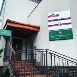 Fasada budynku z kilkoma tablicami informacyjnymi różnych kancelarii prawnych, schody wejściowe z metalową balustradą, Lubin.