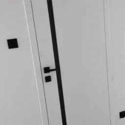 Białe drzwi wewnętrzne z czarnymi akcentami: klamka, pasek dekoracyjny i włącznik światła, widoczne z bliska pod kątem.