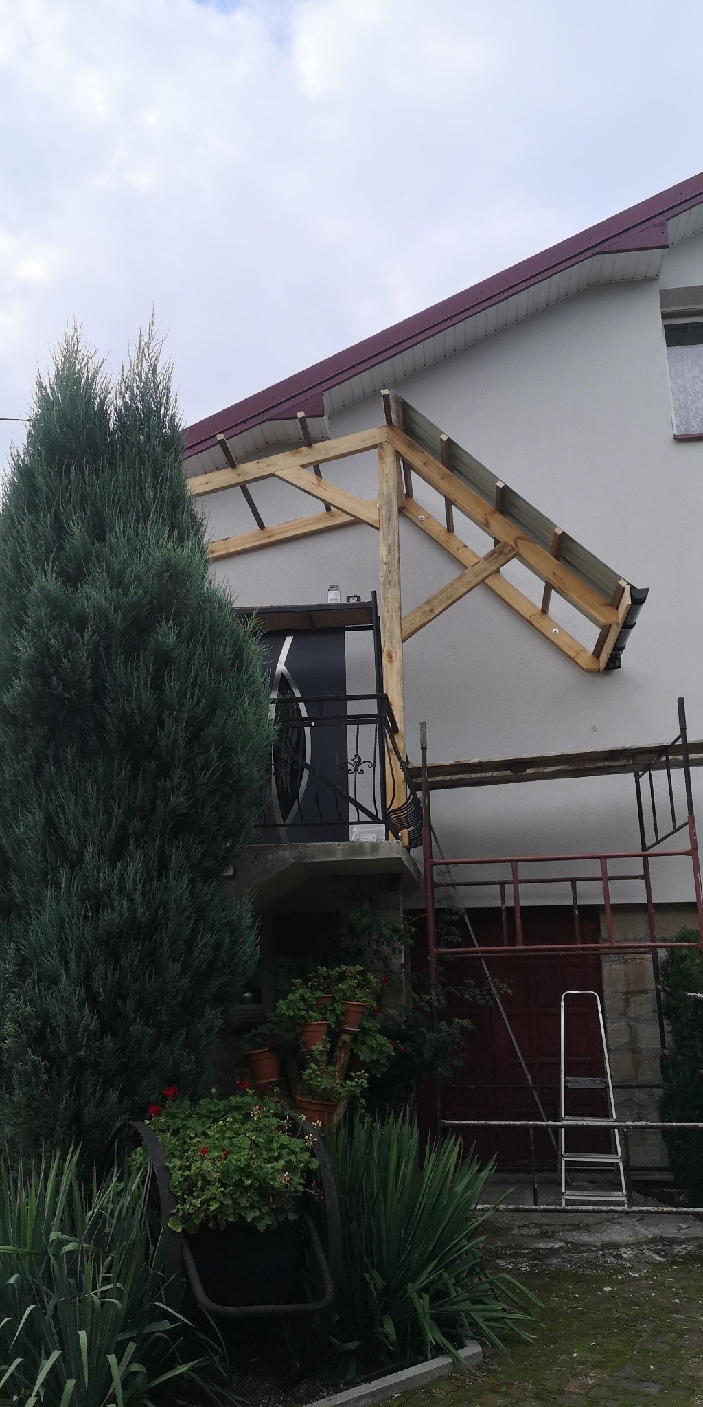 Montaż zadaszenia nad wejściem do domu w Stalowej Woli, widoczne drewniane elementy konstrukcyjne i rusztowanie.