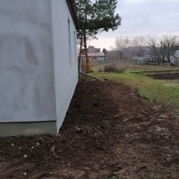 Usług budowlanych / praca/ wykończenia / itd - Świeżo otynkowana elewacja domu jednorodzinnego z widocznymi śladami po pracach, przygotowana do malowania, z obnażoną ziemią wokół fundamentów.