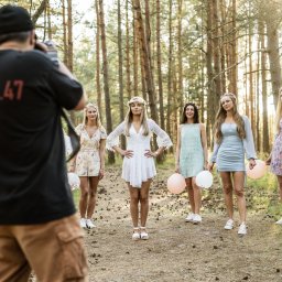 Cezary Gąsiorowski Fotografia - Fotograf z napisem STUDIO 47 na koszulce filmuje grupę młodych kobiet w leśnej scenerii, trzymających balony.