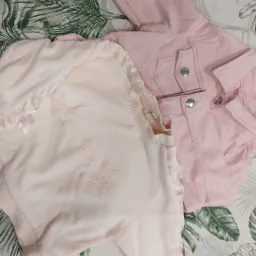 Dwa elementy damskiej garderoby w odcieniach różu: dzinsowa kurtka i bluza z napisem 'Lovely' na tle tkaniny w tropikalne liście.