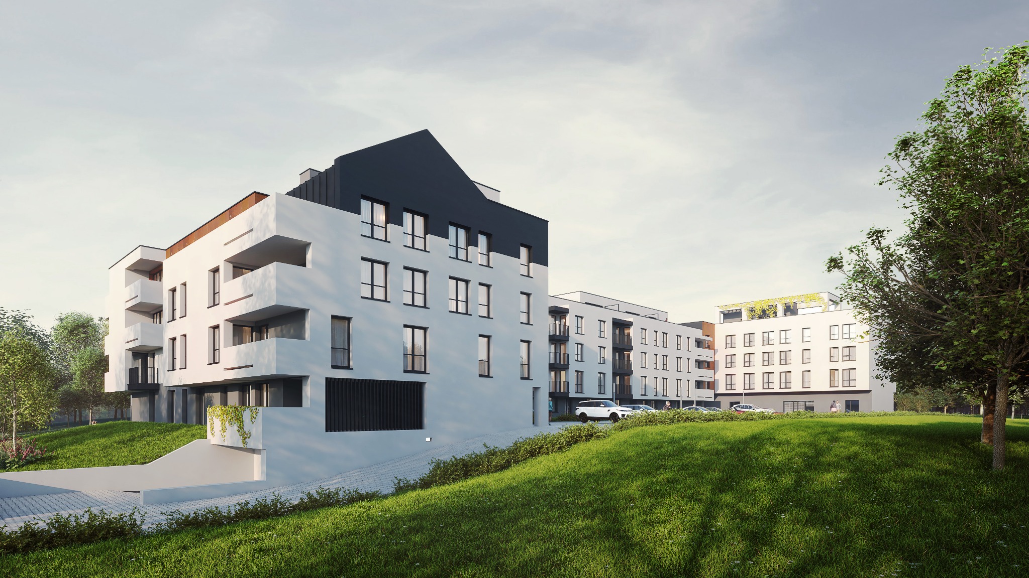 Nowoczesny budynek wielorodzinny z białymi ścianami, czarnymi elementami dachu i balkonami, otoczony zielonym trawnikiem i drzewami, z podziemnym garażem.