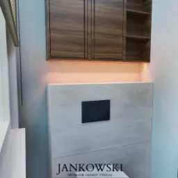 Nowoczesna toaleta w jasnych barwach z drewnianymi szafkami i podświetleniem. Minimalistyczny design, czarny przycisk spłuczki, widok na zewnątrz przez okno.