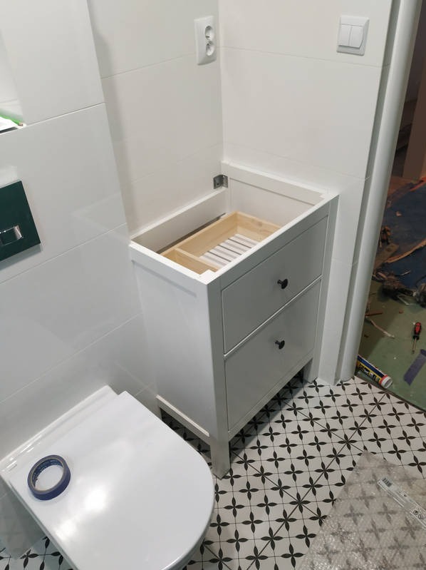 Nietypowy montaż szafki pod umywalkę nablatową w niedużej łazience.