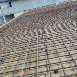 Zbrojenie płyty fundamentowej domu jednorodzinnego z widoczną siatką z prętów stalowych i dystansami z tworzywa sztucznego.