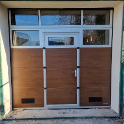 Nowa brama garażowa segmentowa z oknami i drzwiami wejściowymi, wykończona w kolorze drewna, widoczne niedokończone prace wykończeniowe wokół