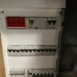 Otwarta skrzynka elektryczna z zabezpieczeniami firmy Legrand, zainstalowana w Oławie, z widocznymi bezpiecznikami i diodami sygnalizacyjnymi.