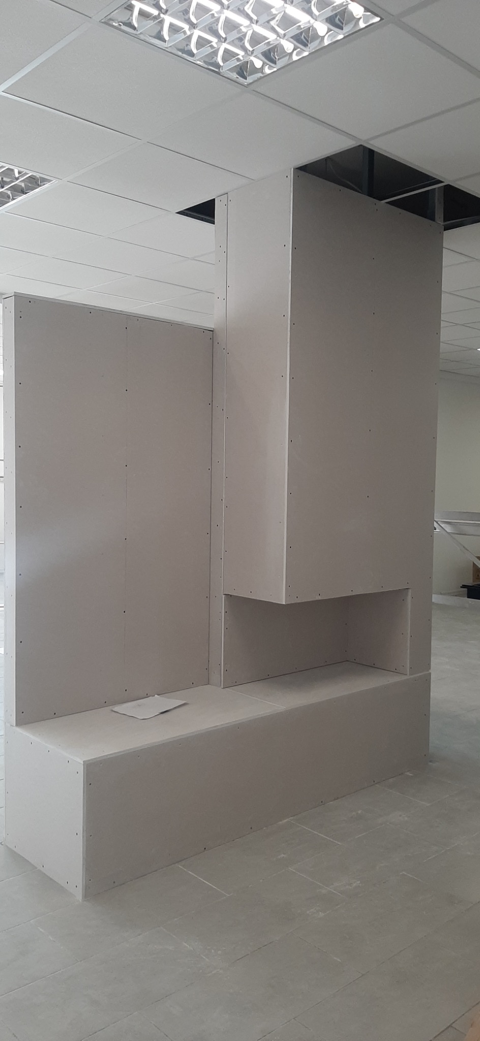 Konstrukcja z płyt karton gips na etapie budowy w biurze, widoczne łączenia płyt, sufit podwieszany z oświetleniem rastrowym.