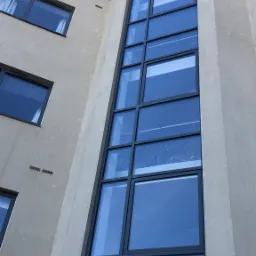 Wysokie okna budynku w Grodzisku Mazowieckim, widok z dołu, odbicie nieba w szybach.