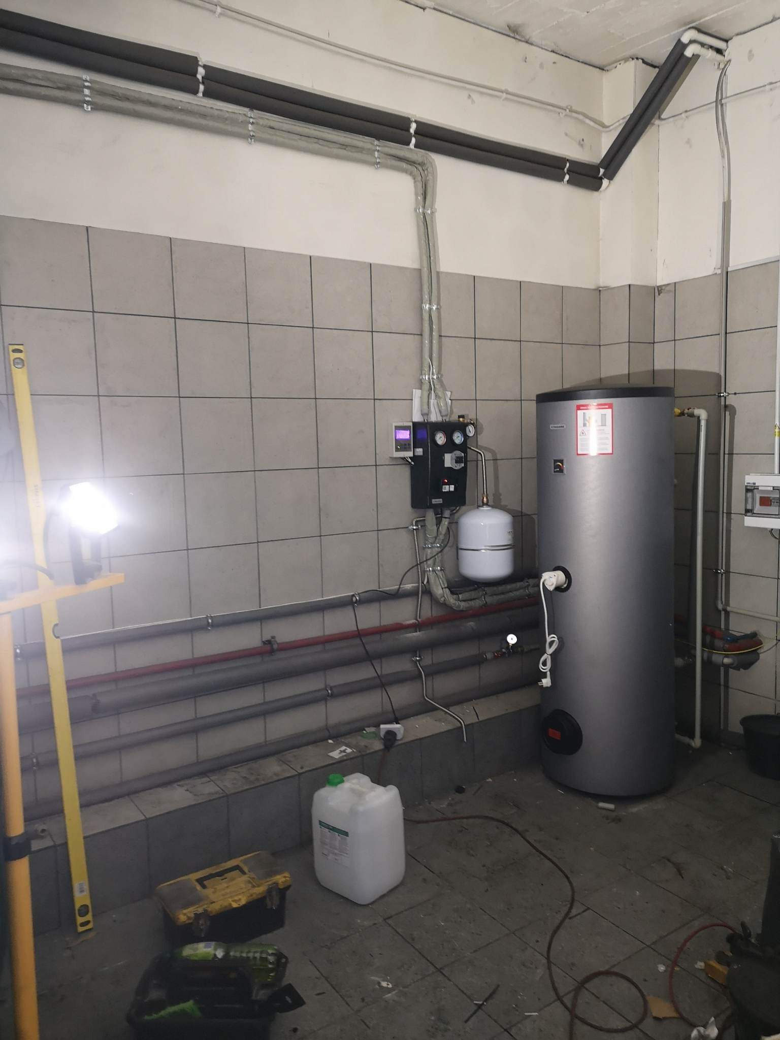 Montaż kolektora słonecznego w kotłowni w Nieborowie. Widoczny zbiornik akumulacyjny, osprzęt i narzędzia pracy.