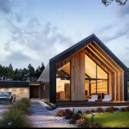 Nowoczesny dom z dużymi przeszkleniami, czarną elewacją i drewnianymi elementami wykończeniowymi, oświetlony z zewnątrz, z podjazdem wyłożonym kamieniami i trawnikiem.
