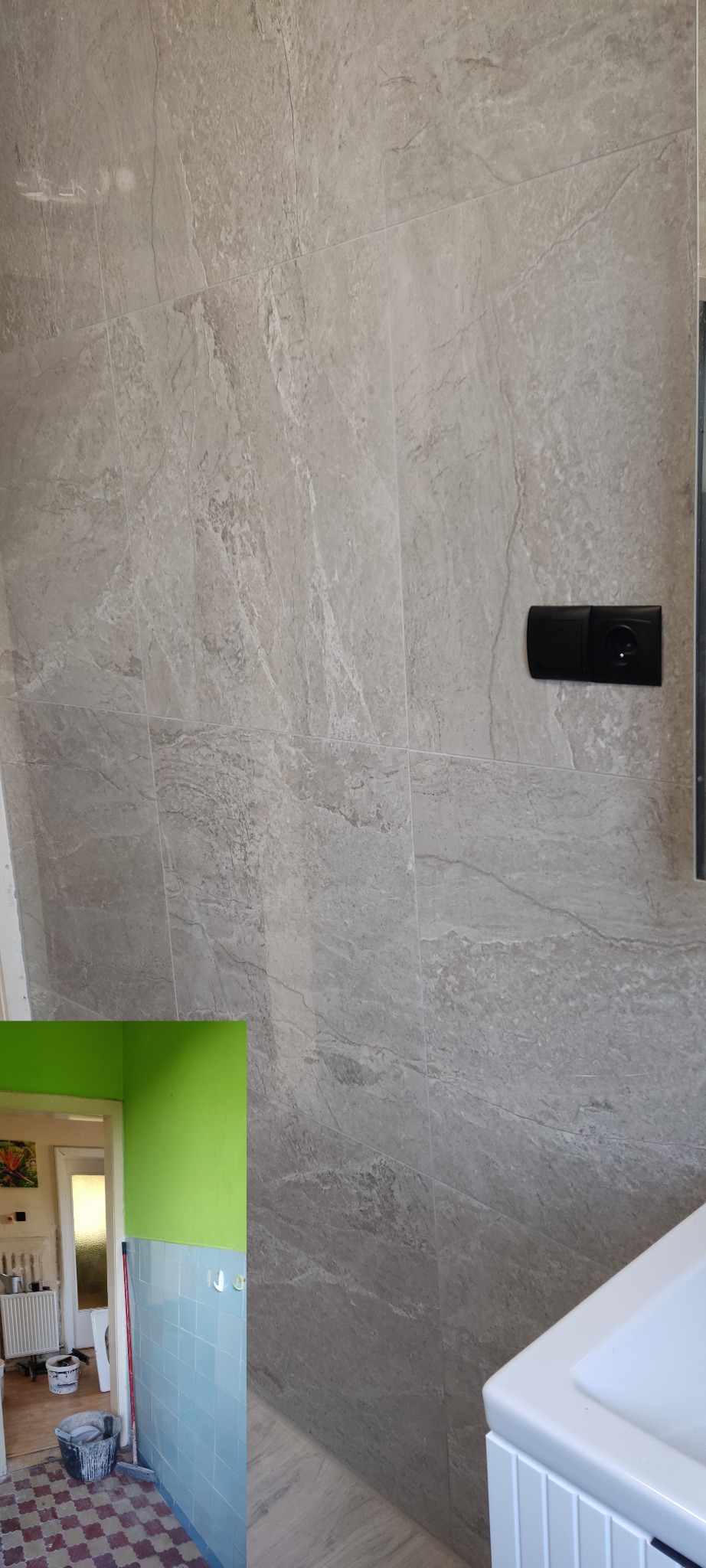 Ściana wyłożona szarymi płytkami imitującymi kamień z widocznym gniazdkiem elektrycznym. W tle fragment sąsiedniego pomieszczenia z niebieskimi płytkami i zieloną ścianą.