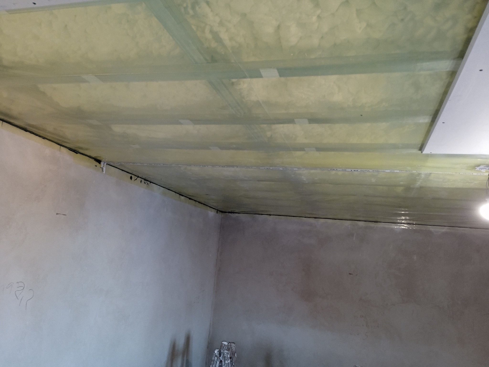 Montaż sufitu podwieszanego z płyt kartonowo-gipsowych, widoczne profile i izolacja wełną mineralną, ściany w trakcie szpachlowania i przygotowania do malowania.