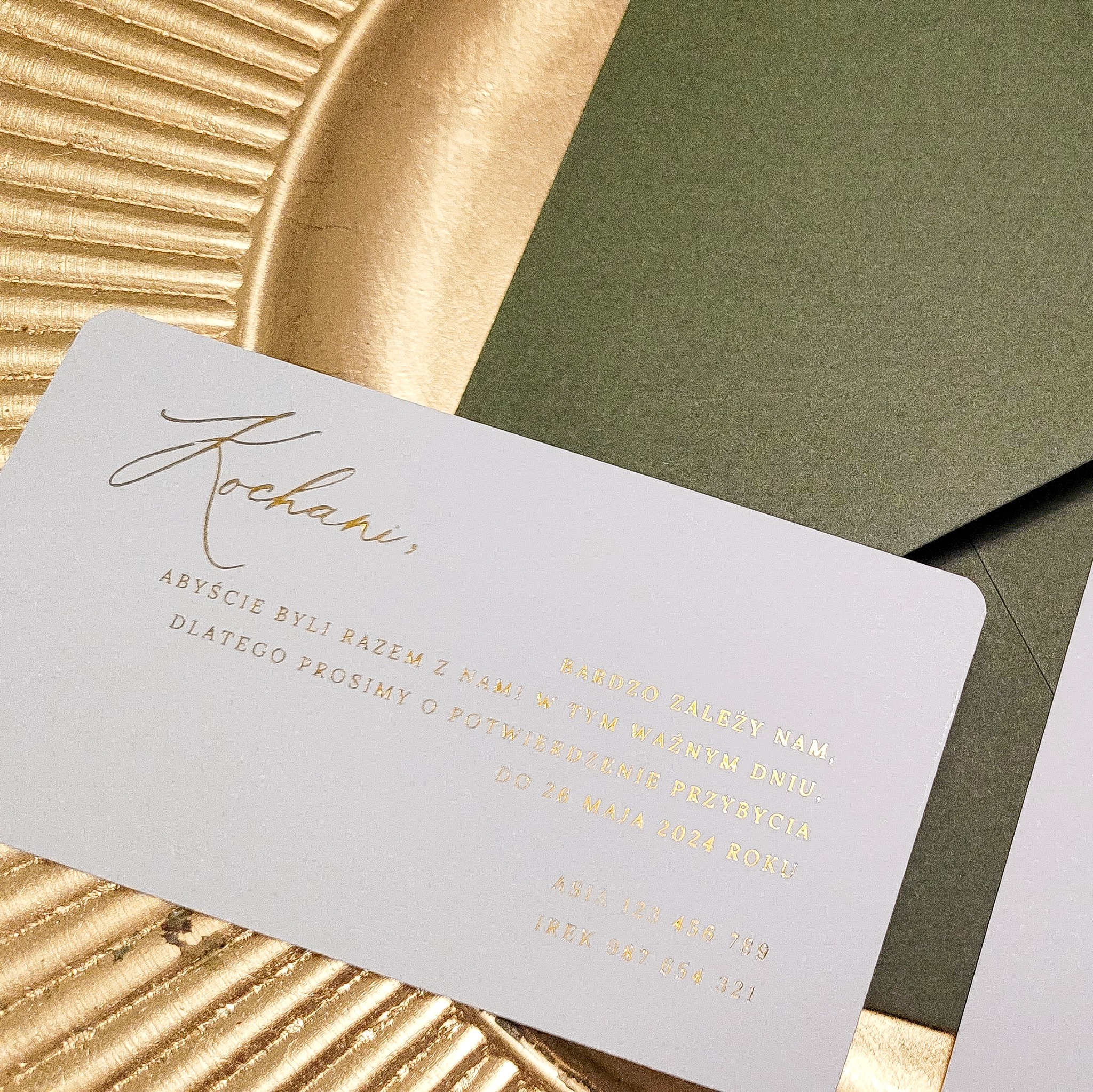 Eleganckie zaproszenie ślubne z zieloną kopertą i złotym napisem na teksturowanym złotym tle.