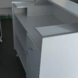 Biała zabudowa meblowa łazienkowa z szafkami i półkami, z umywalką nablatową w tle, widoczne okrągłe, kryształowe uchwyty szafek.