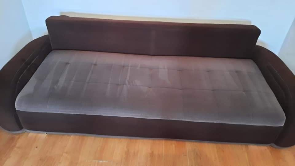 Brązowa kanapa z szarą tapicerką po czyszczeniu, widoczne ślady wilgoci po praniu na siedzisku.