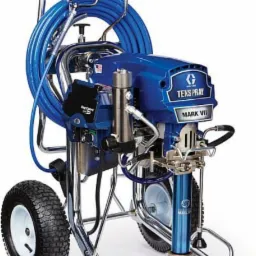 Profesjonalny agregat malarski TexSpray Mark VII na chromowanym wózku z niebieskim wężem i pistoletem natryskowym, widoczne logo producenta Graco.