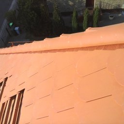 DELA-DACH/SERWIS - Nowy, pomarańczowy dach z okrągłych dachówek z widokiem na rynnę i otoczenie budynku z perspektywy z góry.