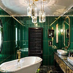 Krzysztof Augustyn - Luksusowa łazienka w odcieniach szmaragdu i złota: wolnostojąca wanna, marmurowe blaty, dekoracyjne lustra i kryształowe lampy wiszące tworzą elegancki klimat.