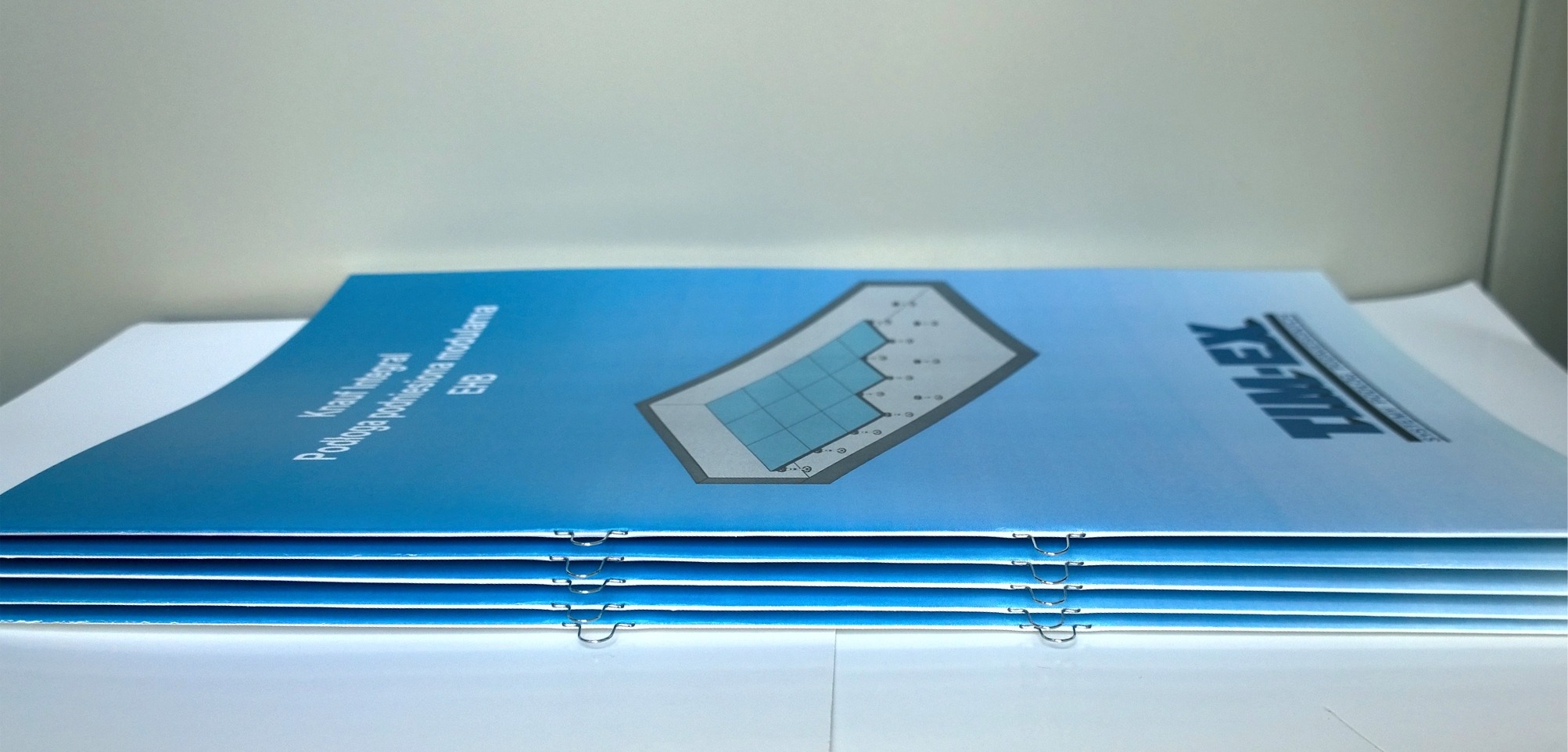 Stos broszur firmowych z Warszawy, zszytych metalowymi zszywkami, z grafiką prezentującą przekrój podłogi podniesionej i logo TIM-EX.