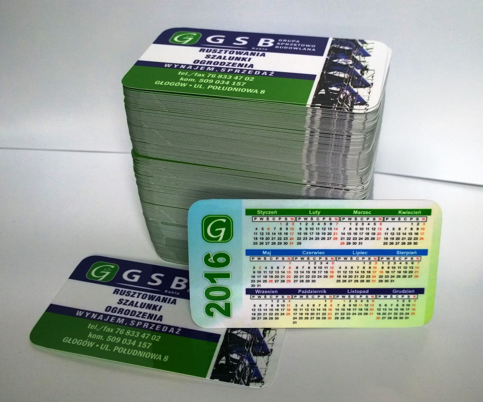 Stos wizytówek firmy GSB Kukla z kalendarzem 2016, z zielono-białym motywem i informacjami o rusztowaniach, szalunkach i ogrodzeniach na wynajem i sprzedaż, z adresem w Głogowie.