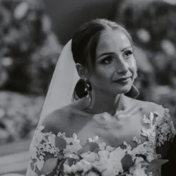 Czarno-białe ujęcie panny młodej w Złoczewie, z bukietem i welonem, spoglądającej w bok z lekkim uśmiechem i łzą w oku.