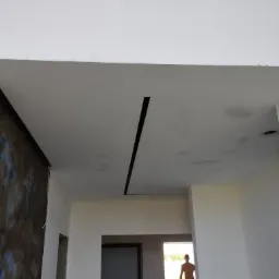 Nowoczesny sufit z podłużnym czarnym oświetleniem w nowo wykończonym wnętrzu z dekoracyjną ścianą w odcieniach brązu i błękitu.