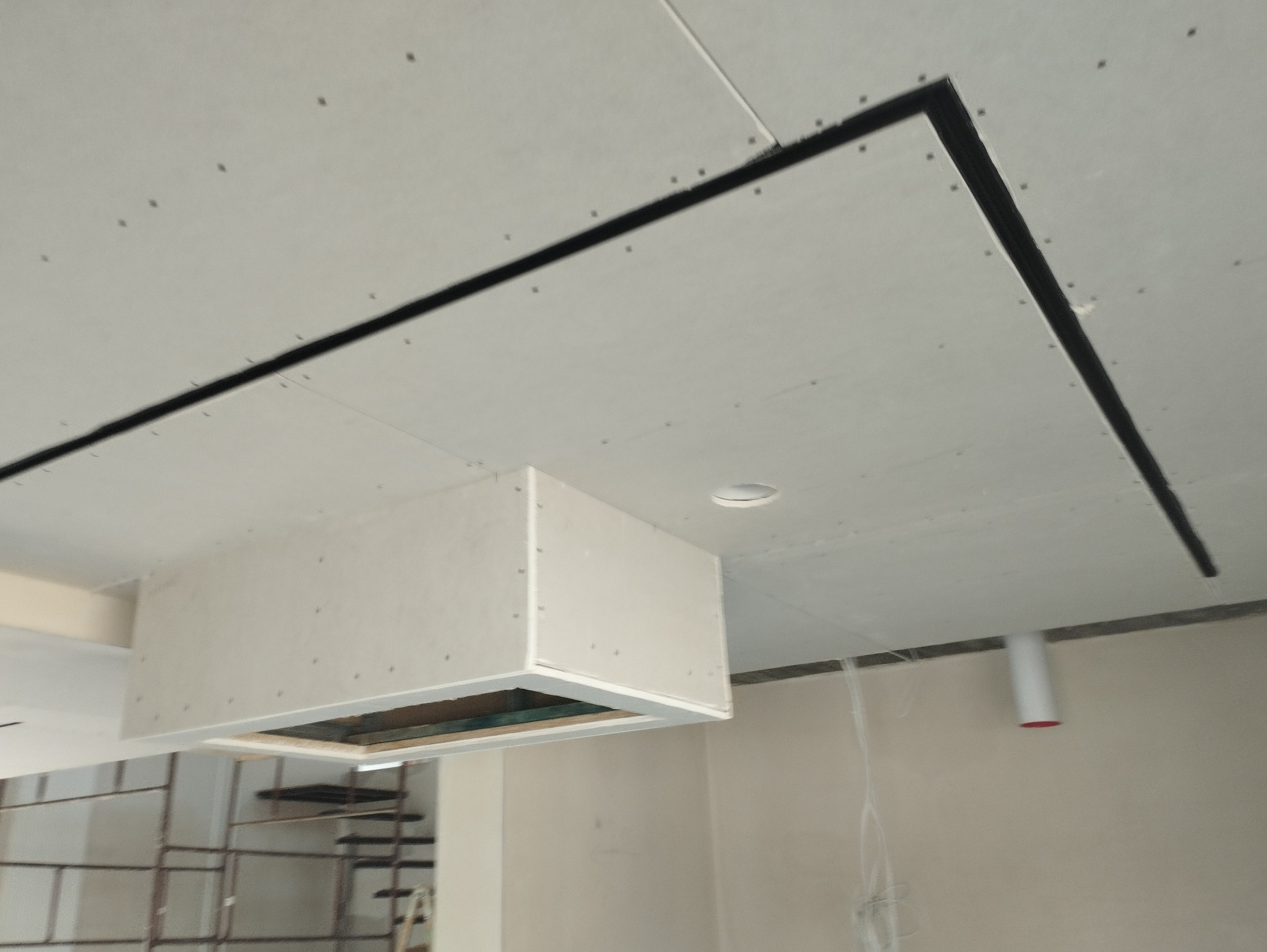 Montaż sufitu podwieszanego z płyt kartonowo-gipsowych, widoczne profile i łączenia, częściowo zabudowana instalacja wentylacyjna, widoczne ślady po szpachlowaniu.