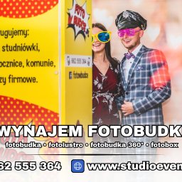 Łukasz Nowak - Uśmiechnięta para w zabawnych okularach pozuje obok fotobudki z napisem 'Wynajem Fotobudki' i danymi kontaktowymi. Mężczyzna w czapce i kraciastej marynarce.